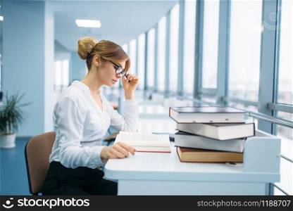 Pretty woman in glasses learning book in library. Female person in reading room, knowledge depository. Pretty woman in glasses learning book, library