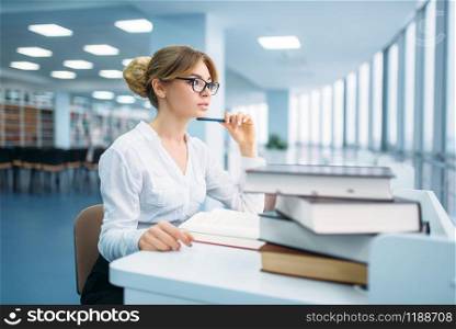 Pretty woman in glasses learning book in library. Female person in reading room, library. Pretty woman in glasses learning book, library