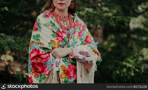 Pretty woman in traditional ukrainian necklace, dress, handkerchief on green nature backdrop. Lady in national costume - vyshyvanka and shawl with pink flowers. High quality . Pretty woman in traditional ukrainian necklace, dress, handkerchief on green nature backdrop. Lady in national costume - vyshyvanka and shawl with pink flowers