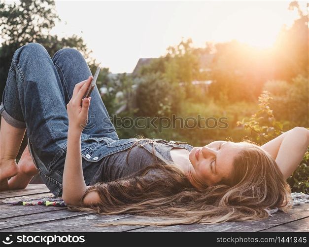 Pretty woman lying on a wooden terrace at sunset background. Closeup, side view, outdoor. Concept of rest and relaxation. Pretty woman lying on a wooden terrace