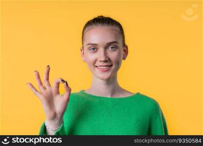 Pretty woman makes hand sign okay, ok gesture. Happy girl, correct perfect choice, great deal, yellow background. Positive female model smiles to camera, approval, trust concept. quality. Pretty woman with OKAY sign, ok gesture. Happy lady, correct choice on yellow