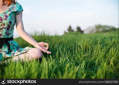 Pretty woman meditate sitting on the grass