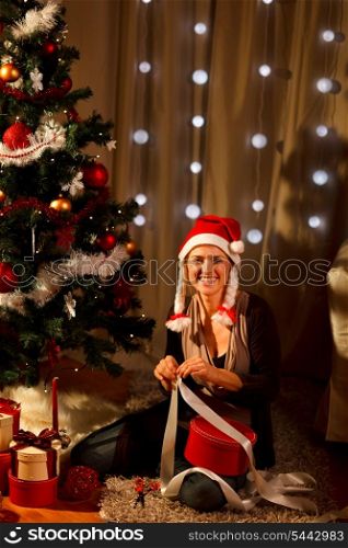 Pretty woman near Christmas tree making gift&#xA;