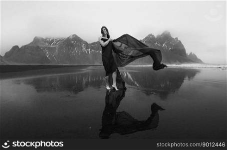 Pretty woman on Reynisfjara beach monochrome scenic photography. Picture of person with hills on background. High quality wallpaper. Photo concept for ads, travel blog, magazine, article. Pretty woman on Reynisfjara beach monochrome scenic photography