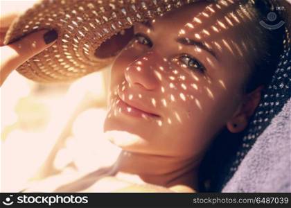 Pretty woman on the beach, closeup portrait of a nice female hides her face from the sun under a straw hat, skin protection, happy healthy summer vacation . Pretty woman on the beach