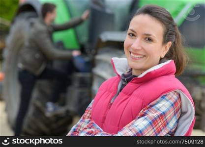 pretty woman posing in front of a tractor