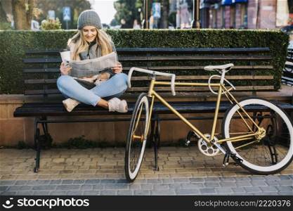 pretty woman reading newspaper near bicycle