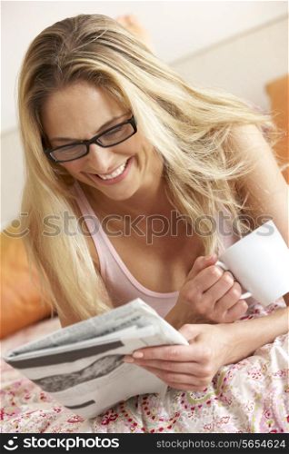 Pretty Woman Relaxing On Bed Reading Newspaper