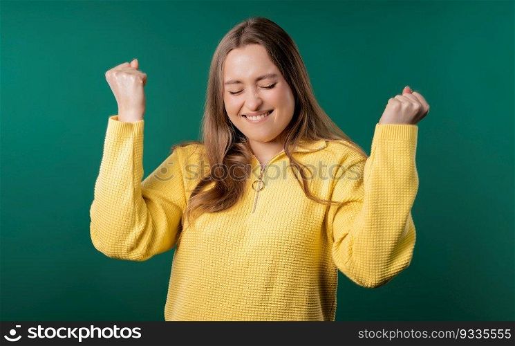 Pretty woman shows triumph yes gesture of victory, she achieved result, goals. Girl glad, happy, surprised excited happy lady on teal background. Jackpot concept. High quality. Pretty woman shows triumph yes gesture of victory, she achieved result, goals