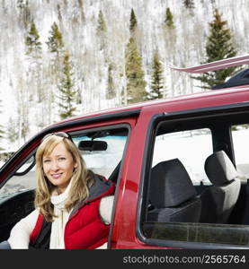 Pretty woman sitting in vehicle wearing winter clothes in rural snowy Colorado smiling.
