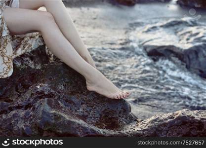 Pretty woman sitting on the sharp rock
