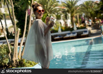 Pretty woman standing next to the swimming pool and enjoying the sun