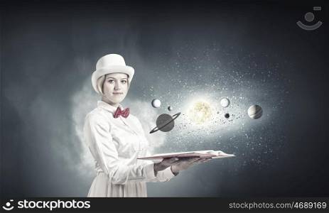 Pretty woman studying astronomy. Young woman in white cylinder and red bowtie with book in hands