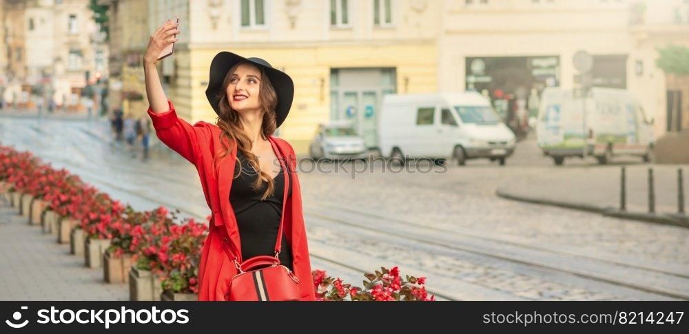 Pretty woman traveler taking selfie portrait by smartphone walking on the city street.. Pretty tourist girl is taking a selfie.
