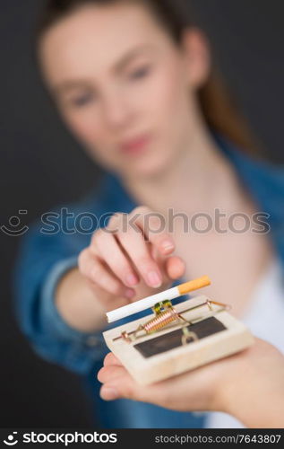 pretty woman trying to reach cigarette laying on mouse trap