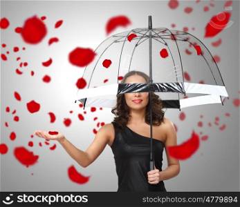 Pretty woman under umbrella with red petals around