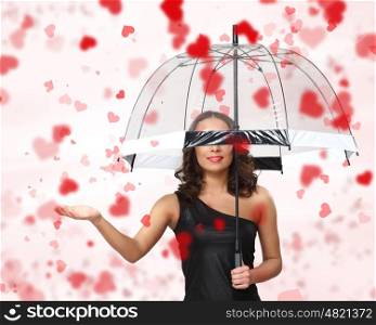 Pretty woman under umbrella with red petals around