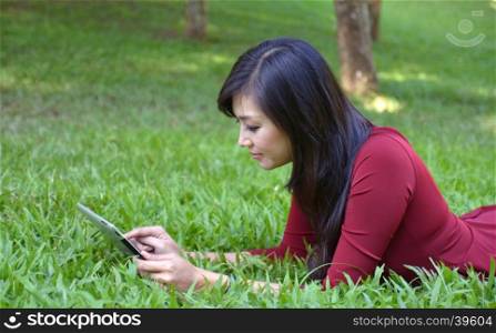 pretty woman using tablet outdoor laying on grass