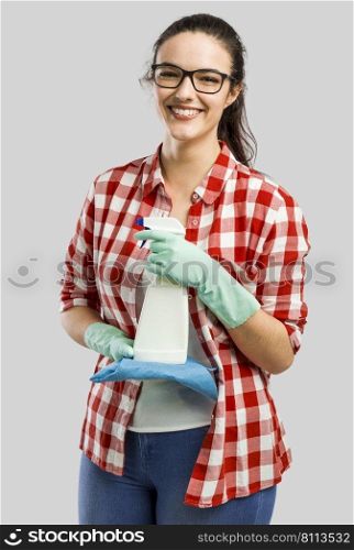 Pretty woman wearing gloves and holding a cleaning spray and a cloth