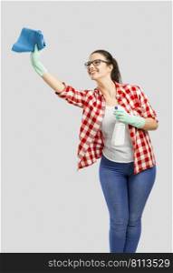 Pretty woman wearing gloves, using a cleaning spray and cleaning the house