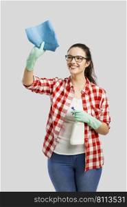 Pretty woman wearing gloves, using a cleaning spray and cleaning the house