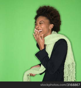 Pretty woman wearing green scarf laughing against green background.