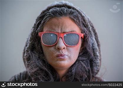 Pretty woman wearing winter outfit and sunglasses. Bemused expression on her face