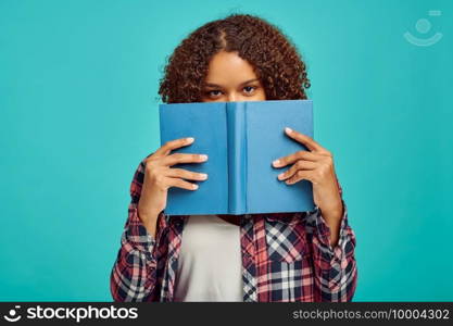 Pretty woman with book, blue background, positive emotion. Face expression, female person looking on camera in studio, emotional concept, feelings. Pretty woman with book, positive emotion