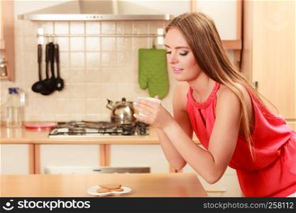 Pretty woman with heart shape gingerbread cookies drinking tea or coffee at home. Gorgeous young girl with hot beverage relaxing in kitchen.. Woman with gingerbread cookies drinking tea coffee