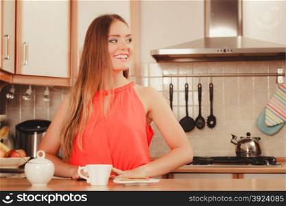 Pretty woman with heart shape gingerbread cookies drinking tea or coffee at home. Gorgeous young girl with hot beverage relaxing in kitchen.