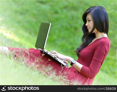 pretty woman with laptop on green grass at the garden