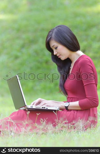 pretty woman with laptop on green grass at the garden