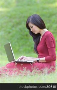 pretty woman with laptop on green grass at the garden