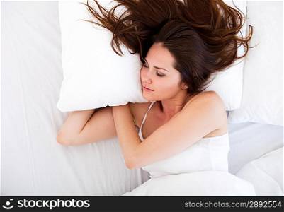 Pretty woman with long brunette hair asleep in bed