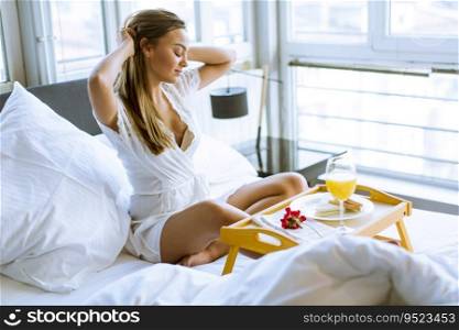 Pretty woung woman having breakfast in bed in the bedroom