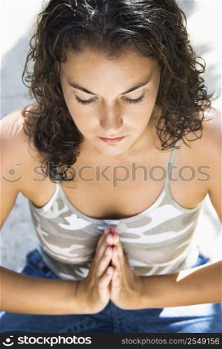 Pretty young adult Caucasian brunette woman practicing yoga with hands at heart center.