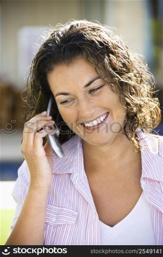 Pretty young adult Caucasian brunette woman talking on cell phone and smiling.