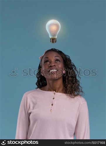 Pretty young african lady standing and thinking with light bulb overhead. Idea concept