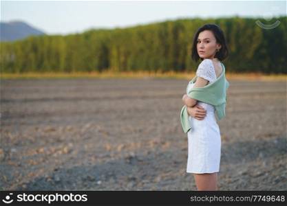 Pretty young Asian woman, walking in the countryside, wearing a white dress.. Asian woman, walking in the countryside, wearing a white dress.