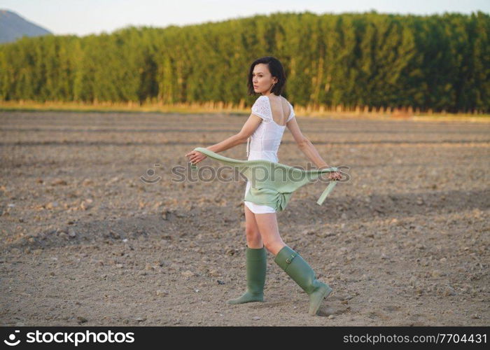 Pretty young Asian woman, walking in the countryside, wearing a white dress and green wellies.. Asian woman, walking in the countryside, wearing a white dress and green wellies.