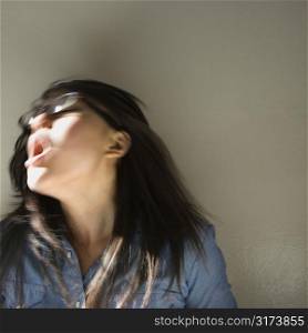 Pretty young Asian woman with mouth open swinging head and hair around.