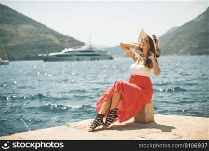 Pretty young attractive woman with a hat poses by the sea in the summer