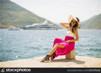 Pretty young attractive woman with a hat poses by the sea in the summer