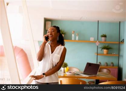 Pretty young black woman using mobile phone in the cafe