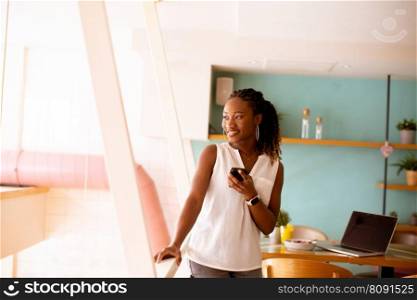 Pretty young black woman using mobile phone in the cafe