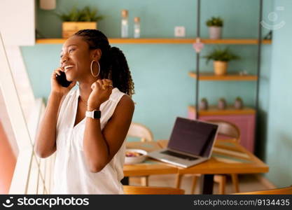 Pretty young black woman using mobile phone in the cafe