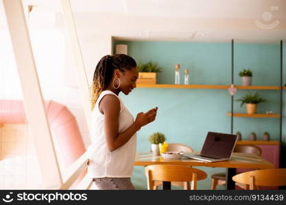 Pretty young black woman using mobile phone in the cafe