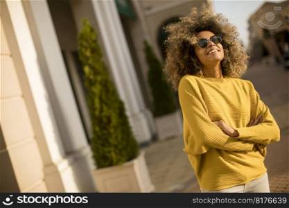 Pretty young black woman with curly hair on the street at sunny day