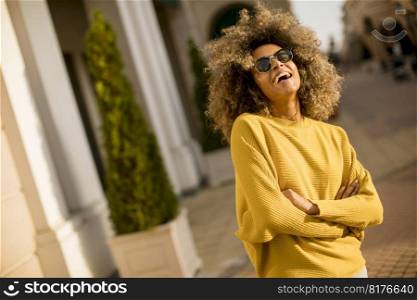 Pretty young black woman with curly hair on the street at sunny day