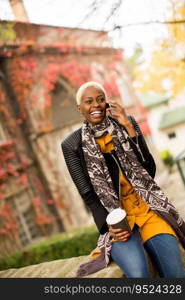 Pretty young black woman with mobile phone and coffee cup